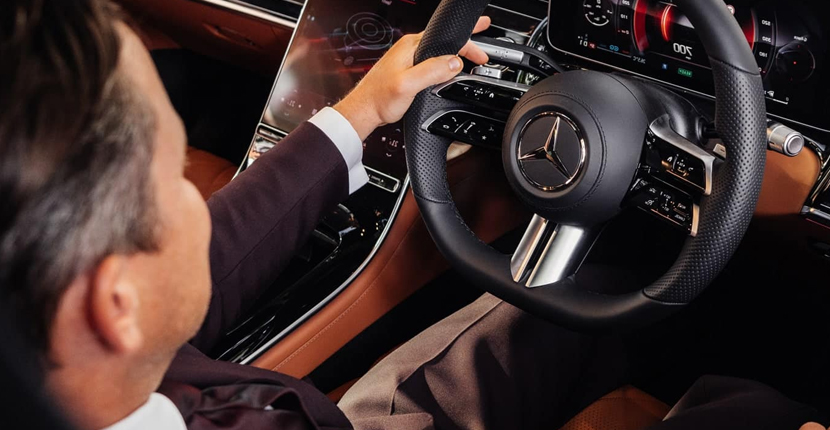 Professional uniformed chauffeur at the wheel of a Mercedes
