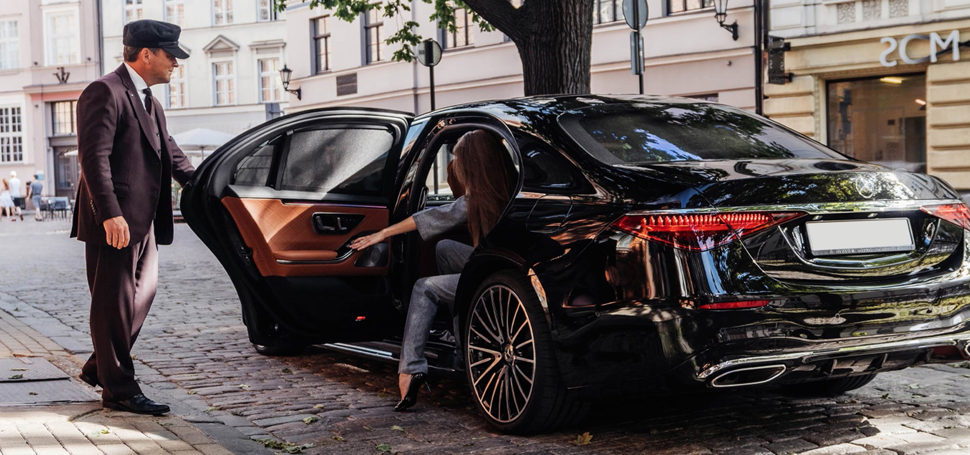 Professional chauffeur opening the door of an executive Mercedes in Manchester
